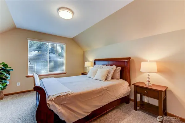 a bed sitting in a bedroom next to a window and lamp