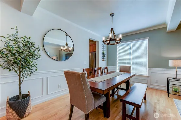 a dining room with wooden floor a chandelier a wooden table and chairs