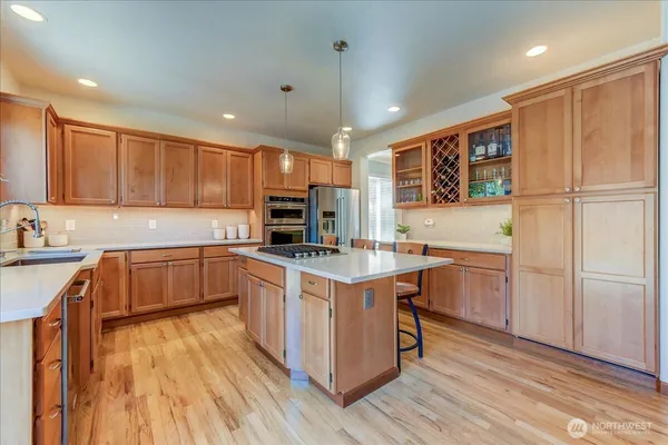 a kitchen with stainless steel appliances granite countertop a stove top oven a sink dishwasher and a refrigerator with wooden floor