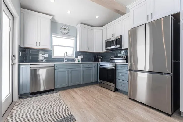 a kitchen with white cabinets stainless steel appliances and a refrigerator