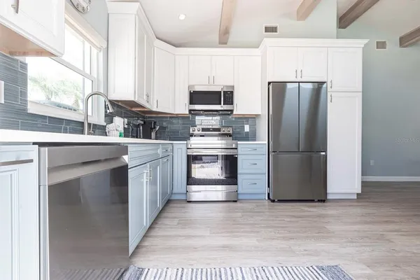 a kitchen with stainless steel appliances granite countertop a refrigerator a stove a sink and a microwave