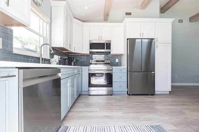 a kitchen with stainless steel appliances granite countertop a refrigerator a stove a sink and a microwave