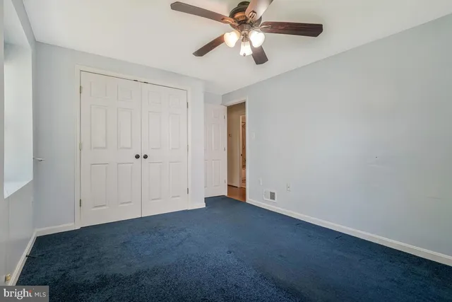 an empty room with closet and a chandelier fan