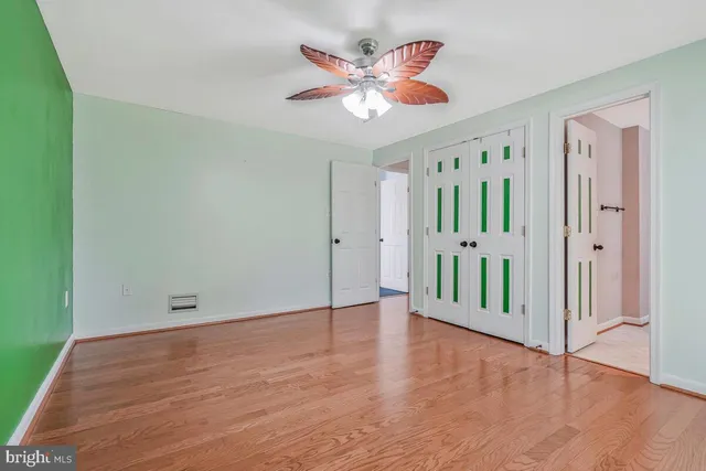 an empty room with wooden floor and a ceiling fan