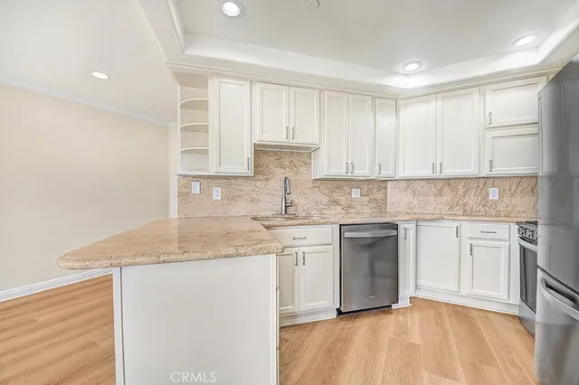 a kitchen with stainless steel appliances granite countertop a stove a sink and white cabinets