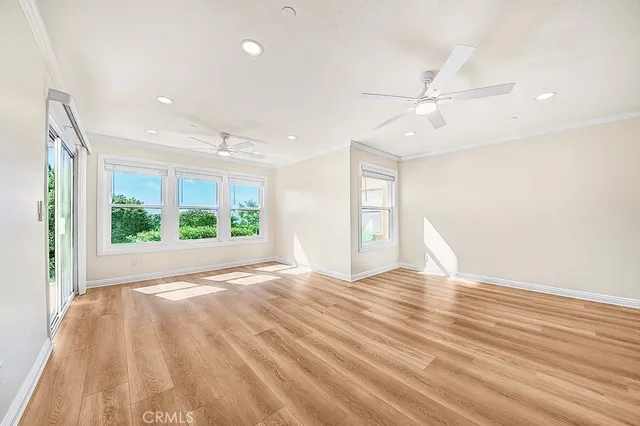 a view of empty room with wooden floor and fan