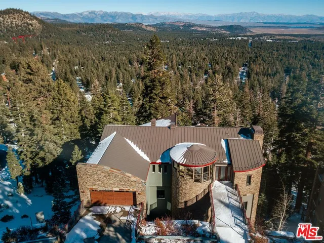 an aerial view of a house with yard and mountain view in back