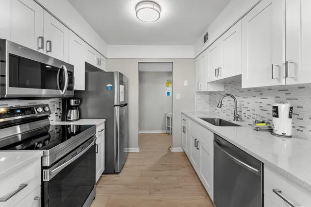 a kitchen with stainless steel appliances a sink dishwasher a refrigerator and a stove