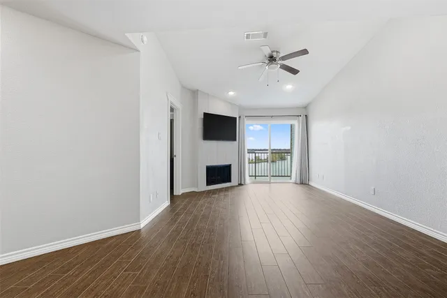 a view of a livingroom with a fireplace a ceiling fan and wooden floor