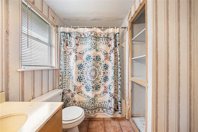 a bathroom with a toilet and a shower curtain