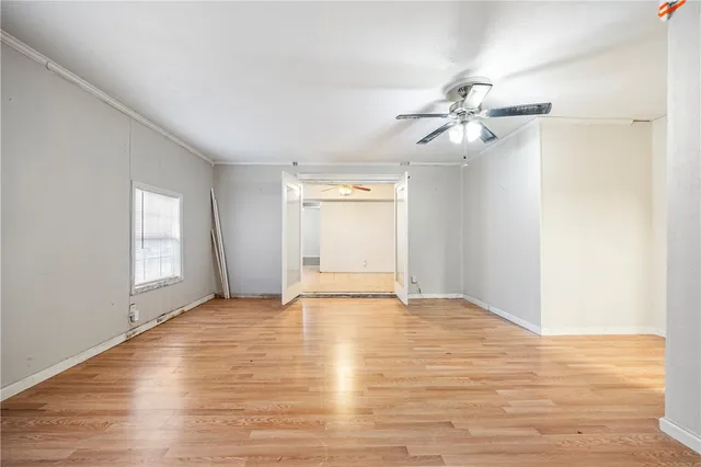a view of empty room with wooden floor and fan