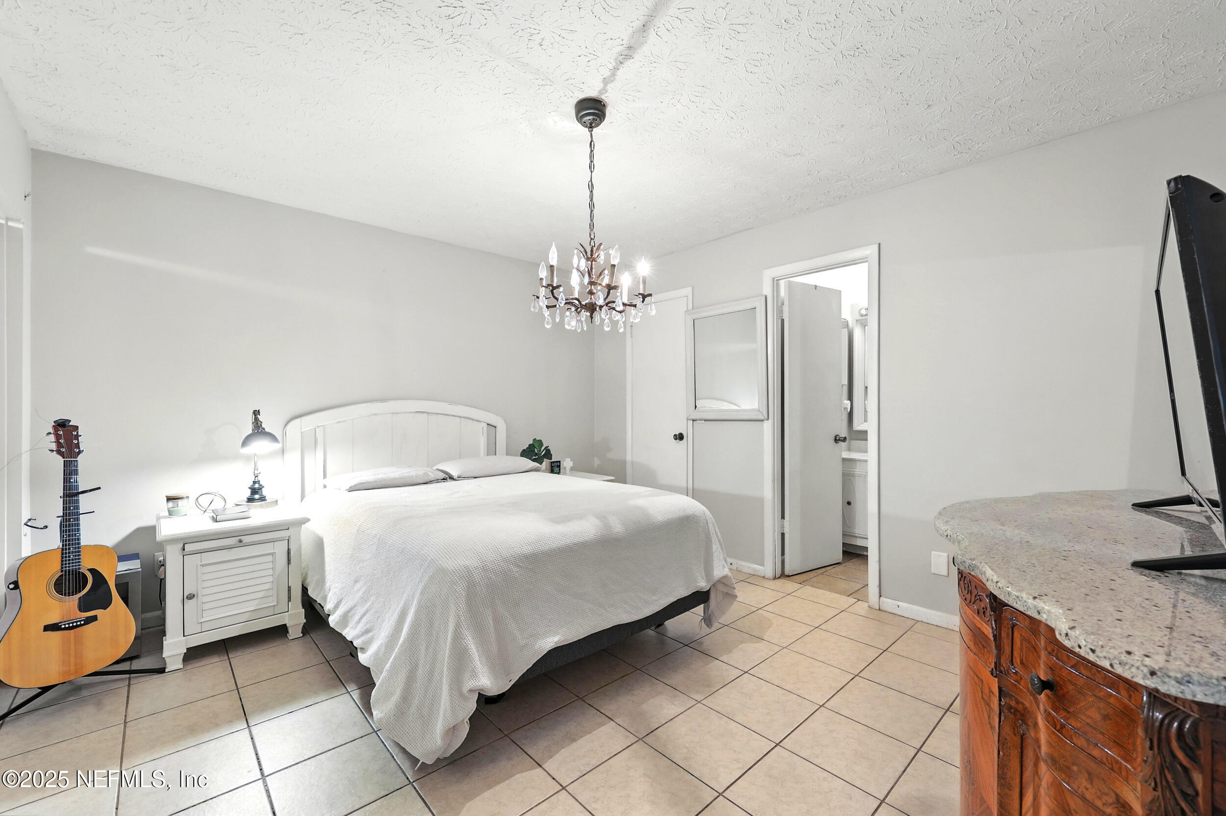 11599 Lake Ride Drive Jacksonville, FL 32223 - Photo 19 of 38 a spacious bedroom with a bed and a chandelier