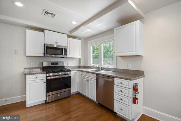 a kitchen with stainless steel appliances granite countertop a stove a sink and a microwave