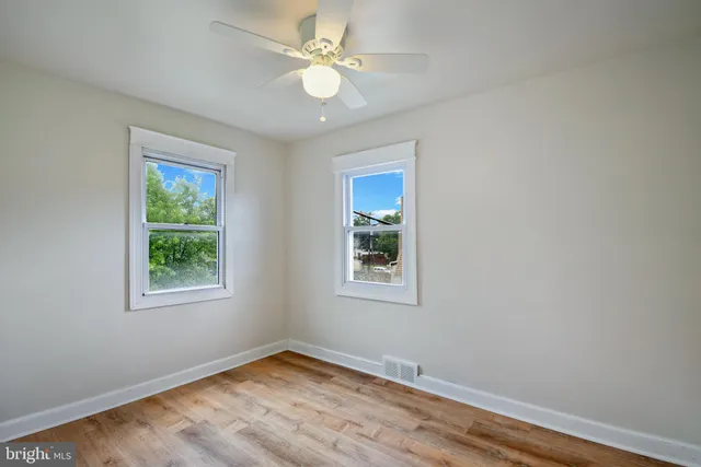 a view of a big room with wooden floor and windows