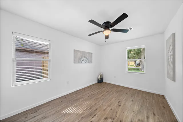 a view of empty room with wooden floor and window