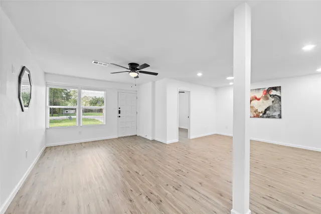 a view of an empty room with wooden floor and a window
