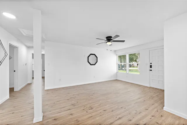 a view of an empty room with wooden floor and a window