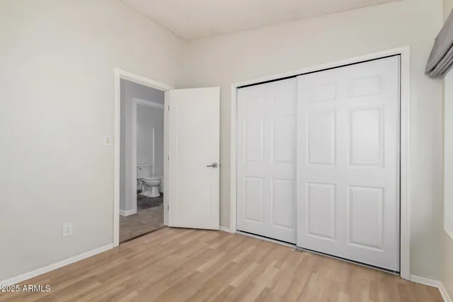 an empty room with wooden floor and closet area