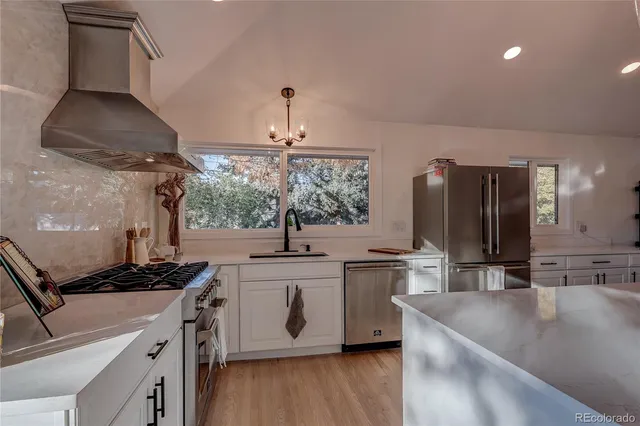 a kitchen with stainless steel appliances granite countertop a sink a stove and a refrigerator
