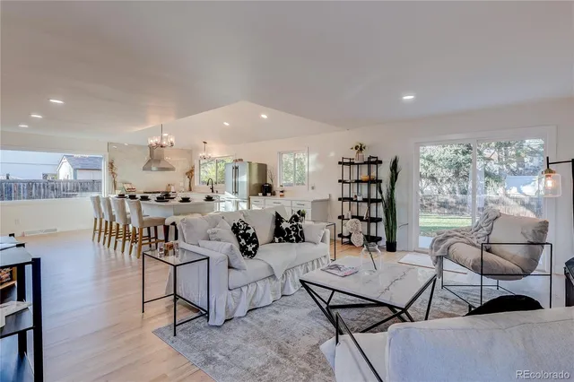 a living room with furniture kitchen view and a large window