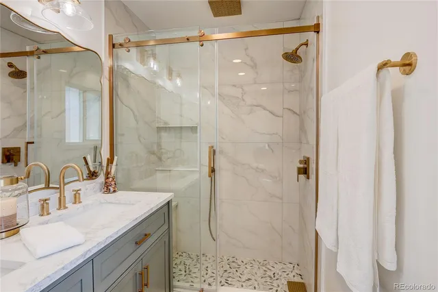 a bathroom with a granite countertop shower sink vanity and mirror