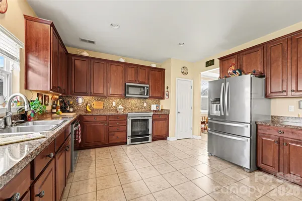 a kitchen with granite countertop a refrigerator stove top oven and sink