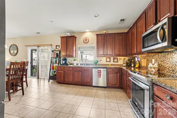 a kitchen with stainless steel appliances granite countertop a stove top oven a sink dishwasher and cabinets