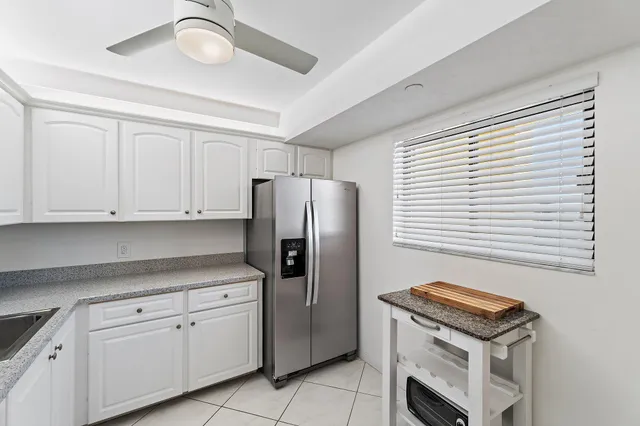 a kitchen with stainless steel appliances granite countertop a refrigerator a sink and white cabinets