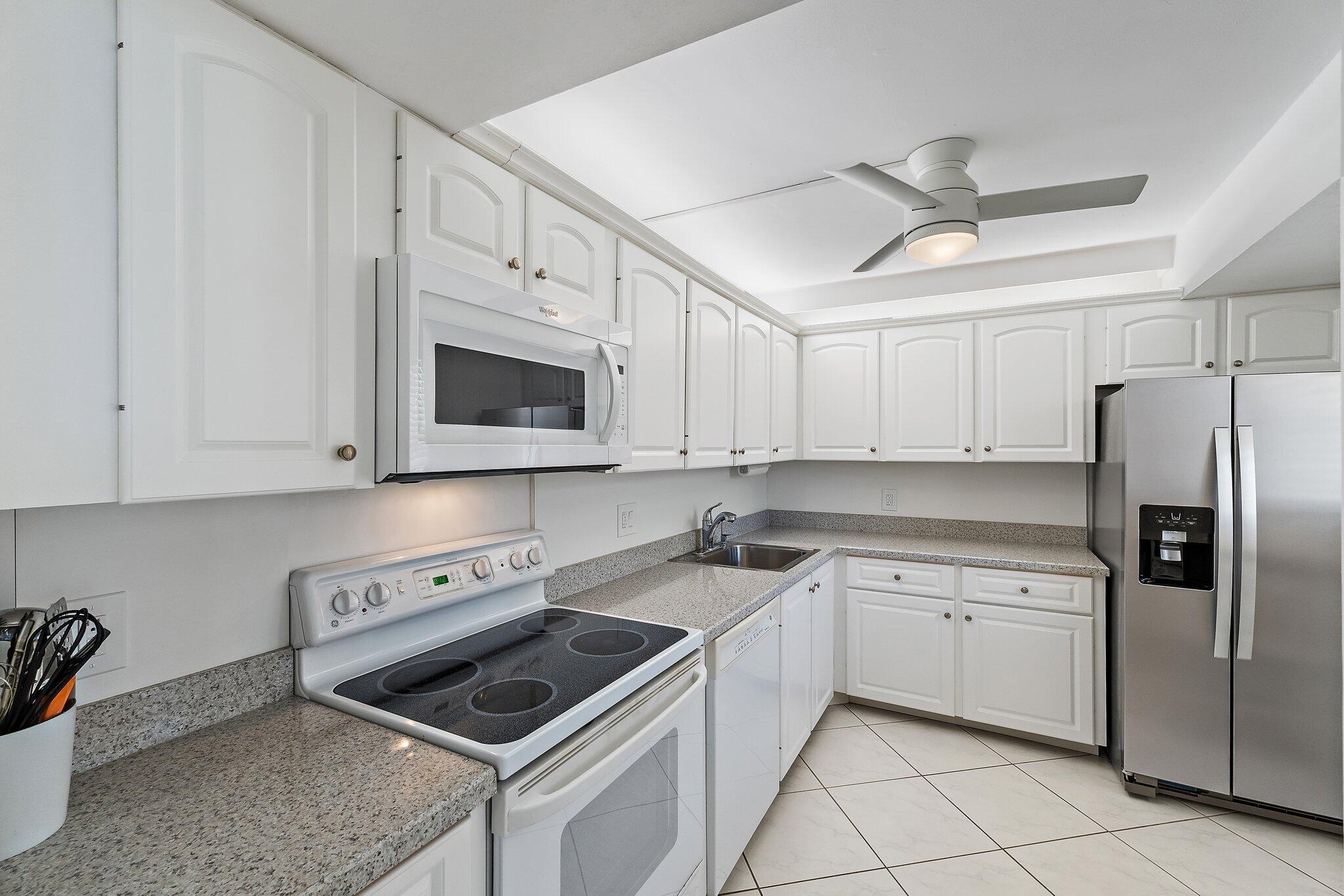 100 Ocean Trail Way, Unit 405 Jupiter, FL 33477 - Photo 16 of 38 a kitchen with white cabinets and appliances