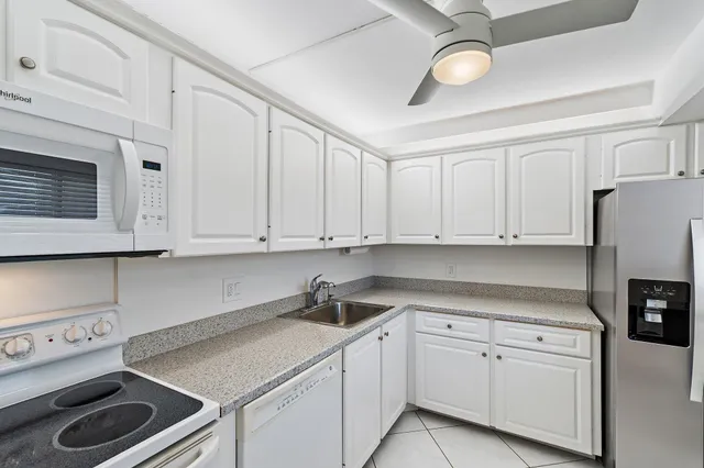 a kitchen with stainless steel appliances granite countertop a sink a stove and white cabinets