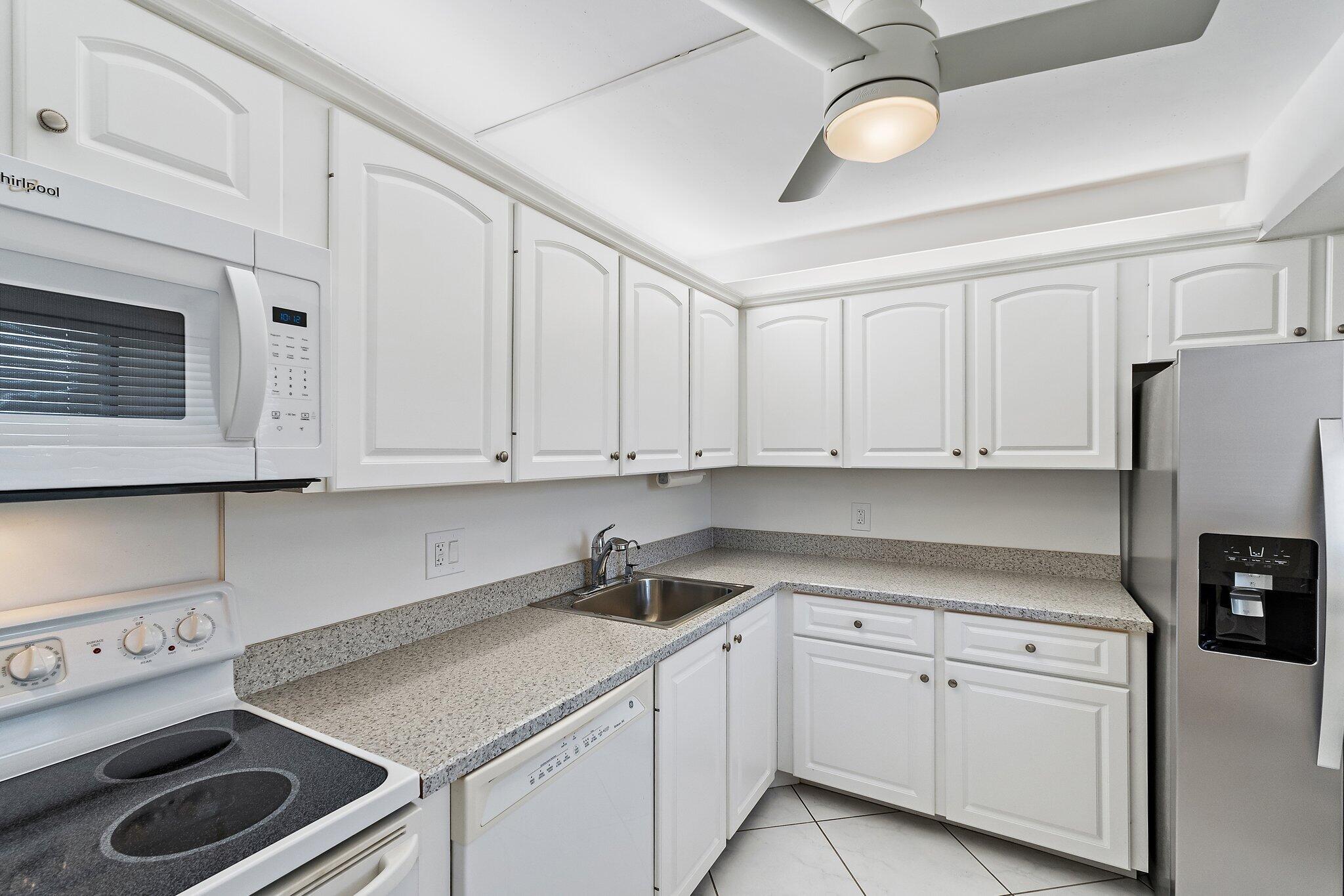 100 Ocean Trail Way, Unit 405 Jupiter, FL 33477 - Photo 17 of 38 a kitchen with stainless steel appliances granite countertop a sink a stove and white cabinets