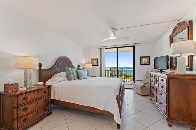 a bedroom with a bed a flat tv screen and dresser next to a window