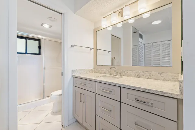 a bathroom with a granite countertop sink a toilet and a mirror