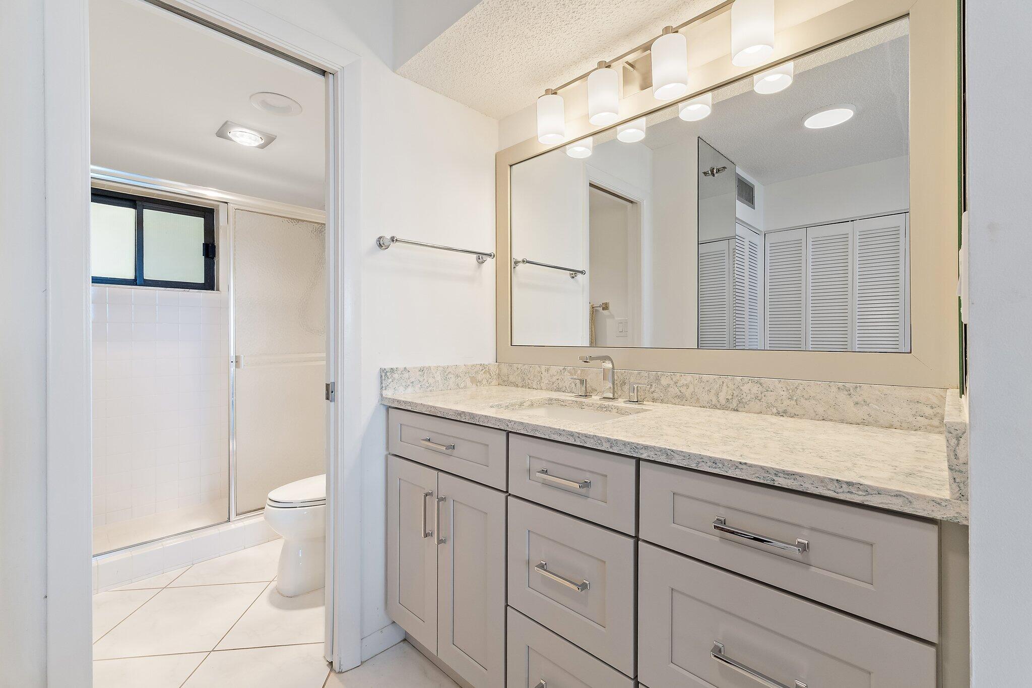 100 Ocean Trail Way, Unit 405 Jupiter, FL 33477 - Photo 25 of 38 a bathroom with a granite countertop sink a toilet and a mirror