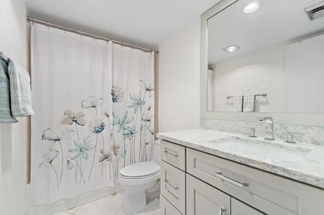 a bathroom with a granite countertop sink a toilet and a shower