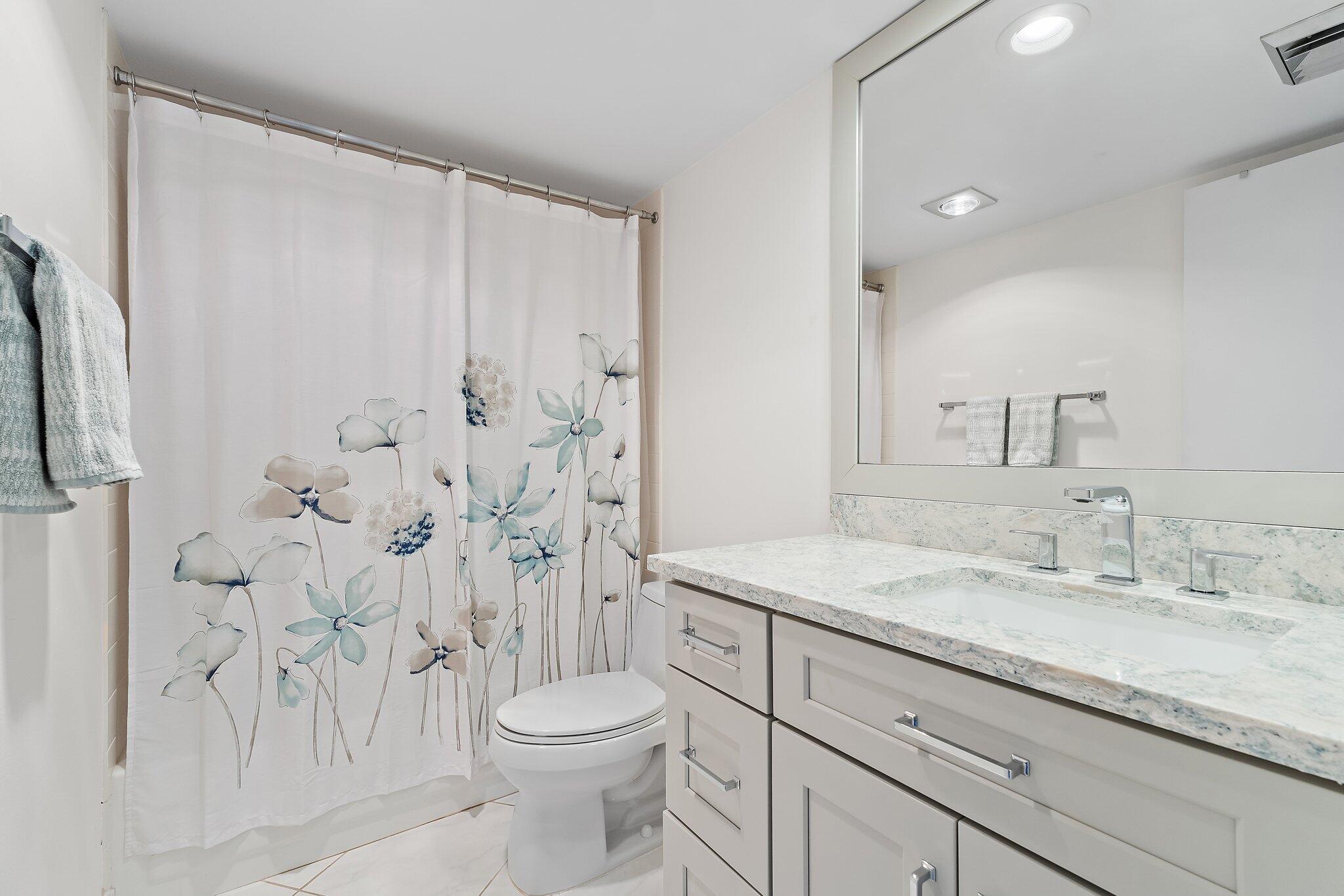 100 Ocean Trail Way, Unit 405 Jupiter, FL 33477 - Photo 29 of 38 a bathroom with a granite countertop sink a toilet and a shower