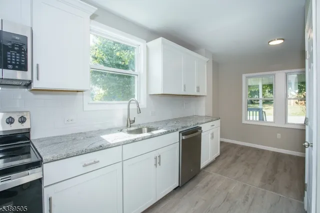 a kitchen with white cabinets stainless steel appliances and sink