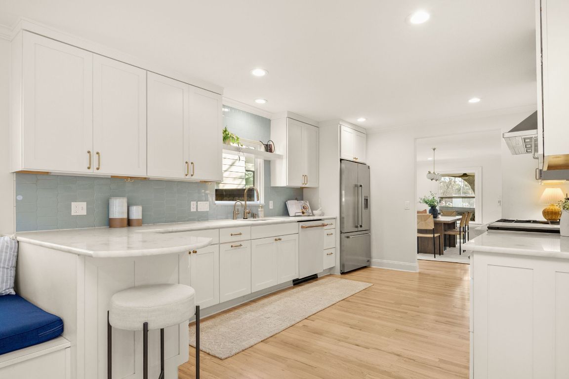 4312 Rosedale Avenue Austin, TX 78756 - Photo 15 of 40 Kitchen with white cabinets, a kitchen breakfast bar, light wood-style flooring, high end refrigerator, and backsplash