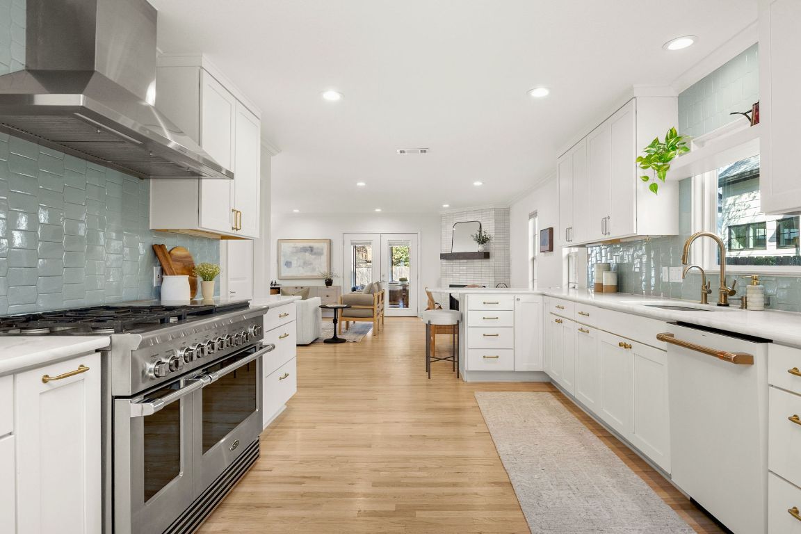 4312 Rosedale Avenue Austin, TX 78756 - Photo 3 of 40 Kitchen featuring white cabinetry, wall chimney range hood, range with two ovens, backsplash, and dishwasher