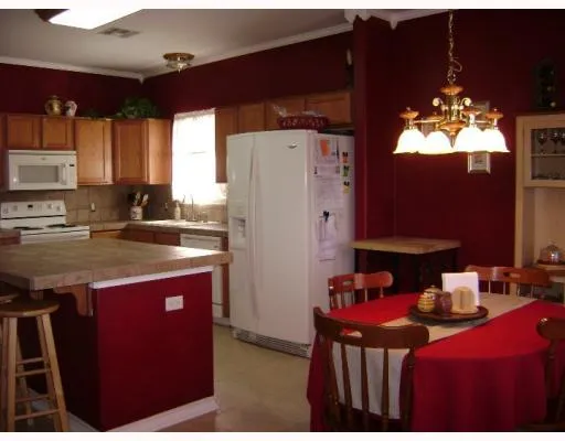 a kitchen with stainless steel appliances granite countertop a refrigerator a sink dishwasher a dining table and chairs with wooden floor