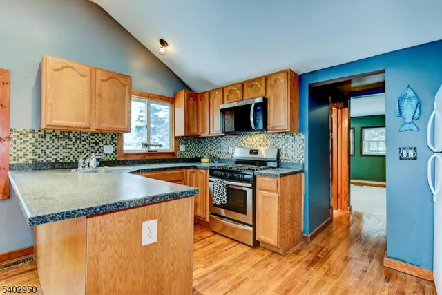 a kitchen with stainless steel appliances granite countertop a stove a sink and a microwave