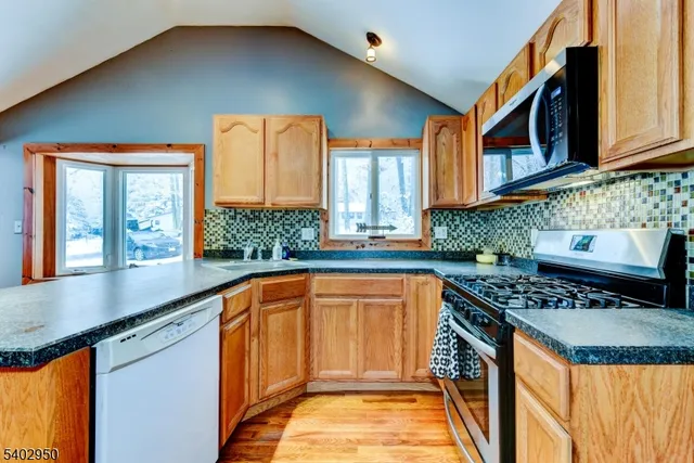 a kitchen with stainless steel appliances granite countertop a stove a sink and a microwave