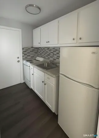 a kitchen with granite countertop white cabinets and white appliances
