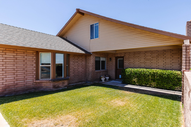1470 Redwood Tree Street St. George, UT 84790 - Photo 37 of 53 Brick exterior with a bay window, covered entry, and manicured shrubbery