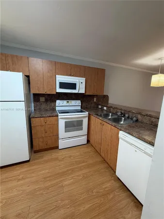 a kitchen with granite countertop a stove a sink and a refrigerator
