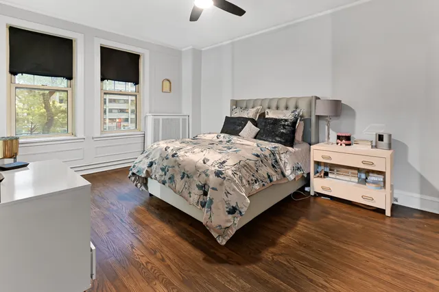 a bedroom with a bed next to a large window with wooden floor