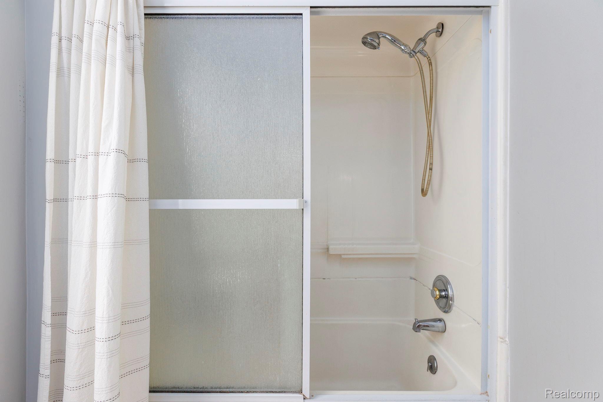 401 Pointe Tremble Road Algonac, MI 48001 - Photo 29 of 40 Bathtub and shower combination featuring a white surround, sliding frosted glass doors, and a chrome shower fixture