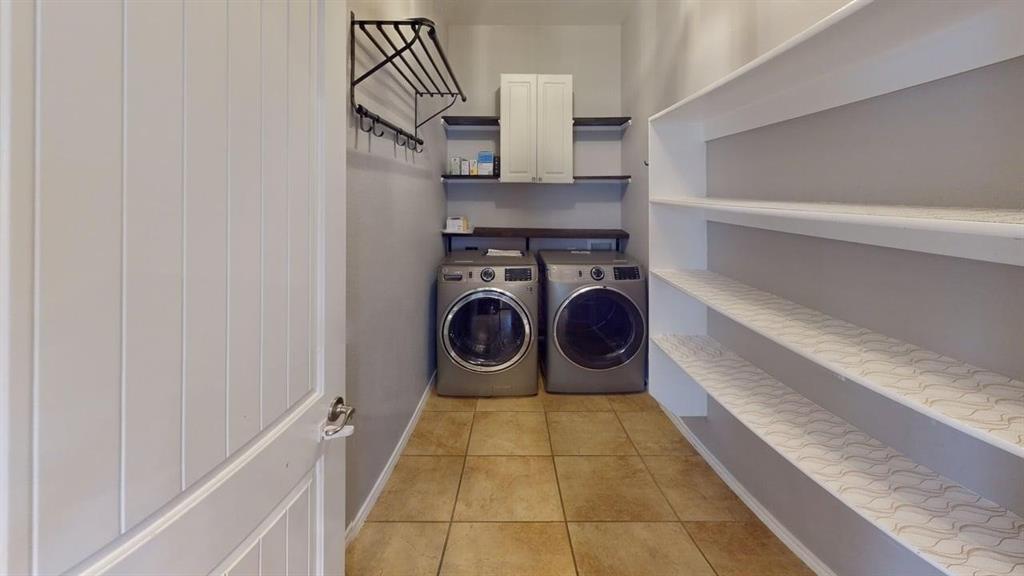 14308 Polo Ranch Street Fort Worth, TX 76052 - Photo 17 of 19 Laundry area featuring tile flooring, built-in shelving, white cabinetry, and a wall-mounted drying rack