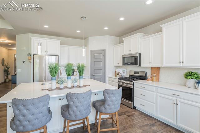 5126 Pring Ranch Road Colorado Springs, CO 80922 - Photo 2 of 32 Bright kitchen with opal baksplash, quartz surfaces, stainless appliances and contemporary pendant lights. Also the oven is convection!