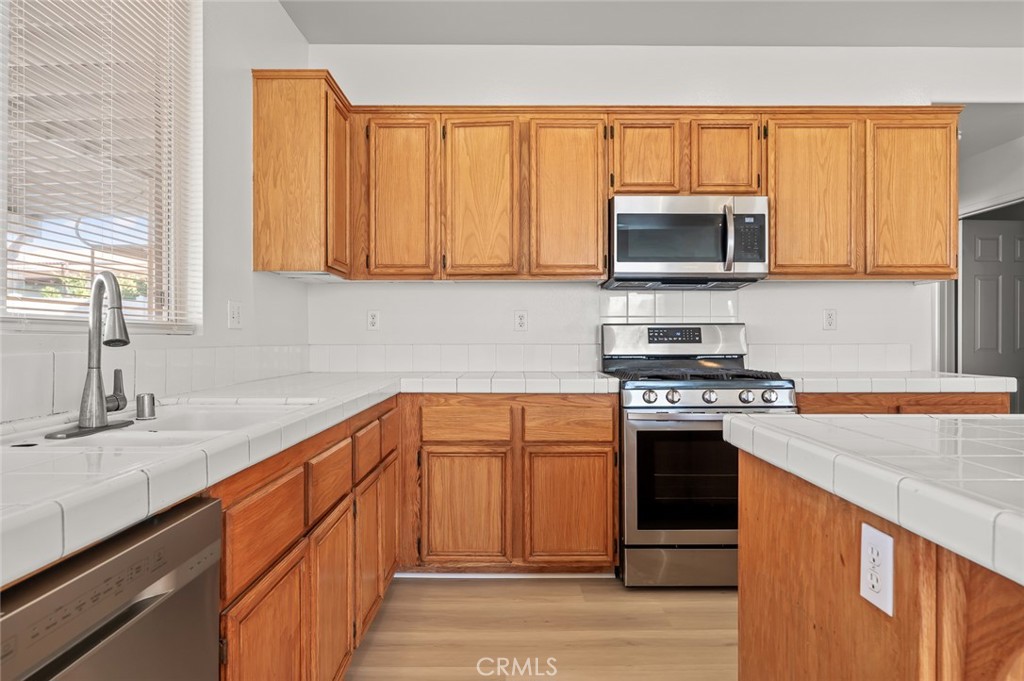 6323 Scalea Court Palmdale, CA 93552 - Photo 18 of 58 a kitchen with stainless steel appliances granite countertop a stove a sink and a microwave